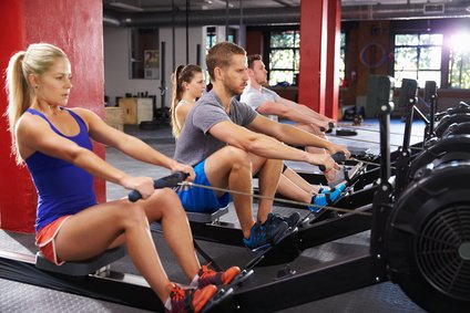 Sportler trainieren am Rudergerät zum abnehmen